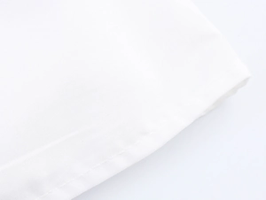 Detailaufnahme der feinen Textur und der sauberen Nähte am weißen Stoffrand der Kleidung