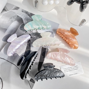 Set of minimalist acrylic claw clips in various marble and jelly colors on a magazine