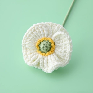 Macro shot of a handmade crocheted white corn poppy flower with yellow and green yarn core