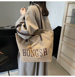 Detailed side view of khaki canvas tote bag with brown leather handles worn by a model