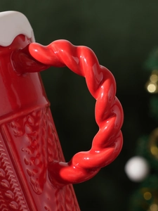 Macro shot of red ceramic mug handle with knitted texture and glossy finish