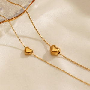 Élégant collier plaqué or 18 carats avec double pendentif cœur sur fond de soie beige