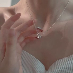 Close-up of a silver heart-shaped pendant necklace worn on a woman's collarbone