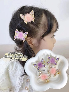 Close-up of moving butterfly hair clip with purple rhinestones and soft pom-pom detail