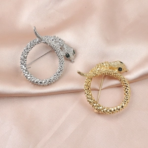 Detail of silver and gold snake brooches with scale texture on pink silk fabric