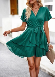 Détail de robe vert foncé à col en V avec taille lacée et ourlet à volants superposés