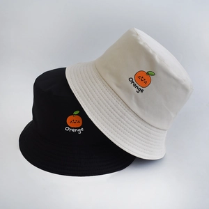 Detail of black and beige reversible bucket hats with orange fruit embroidery