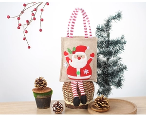 Detail of Christmas gift bag with Santa Claus motif and long striped handles on wood