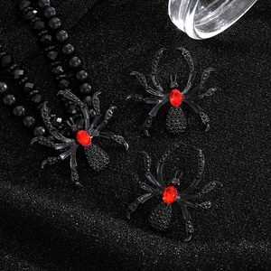 Gothic black metal spider necklace set with striking red faceted gemstones on dark fabric