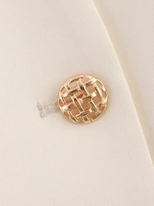 Detailed close-up of a golden woven texture metal button on cream twill fabric