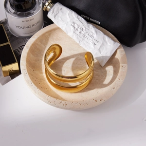 Close-up of 18K gold plated hollow double-layer bangle on a beige stone plate