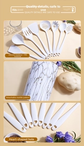Close-up of white silicone kitchen utensils with heart-shaped holes and marble holder
