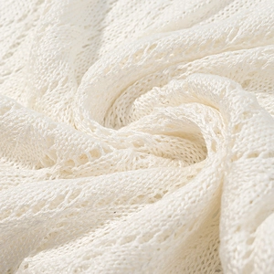 Detailed close-up showing the intricate white knit texture and lace pattern of the dress fabric