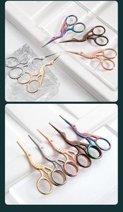 Dettaglio di forbici da ricamo vintage a forma di gru in oro, argento, oro rosa e bronzo