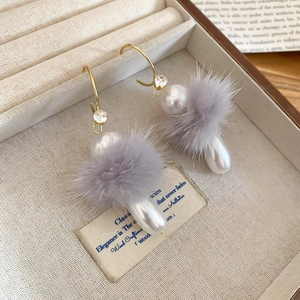 Détail de boucles d'oreilles pompon gris avec perles blanches en forme de goutte