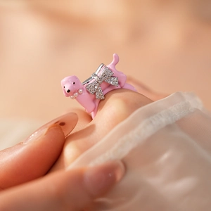Detail of pink enamel dachshund ring with zircon bow and pearl necklace charm