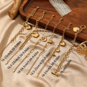 Set of 6 gold heart charm bracelets and paperclip chains on silk fabric display