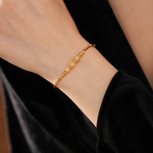 Macro detail of 18K gold-plated bamboo bracelet with three zircon-encrusted bead charms