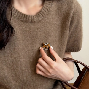 Detailansicht einer braunen Pony-Brosche mit Strasssteinen auf braunem Strickpullover