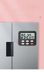 Macro view of digital kitchen timer with magnetic back attached to a silver refrigerator
