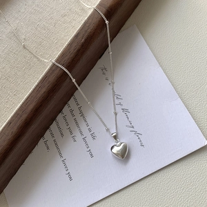 Detail of silver heart pendant necklace with small bead chain on elegant card