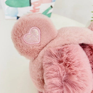 Detail of pink plush earmuffs featuring a shiny sequined heart with iridescent glitter