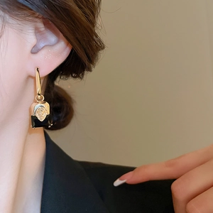 Close-up of vintage gold lion head earrings with rectangular black gemstone on model