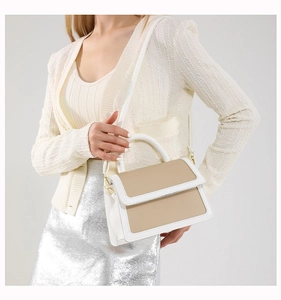 Detail shot of beige and white contrast shoulder bag with metal clasp and detachable strap