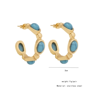 Macro shot of gold C-shaped stainless steel earrings with blue turquoise texture inlays