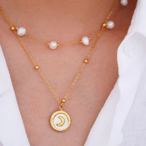 14K gold plated layered necklace with white pearls and moon pendant on woman's neck