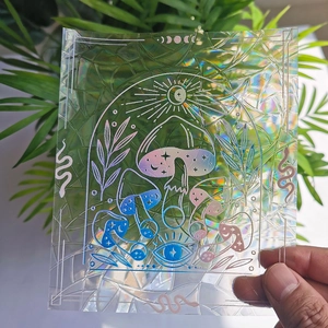 Hand holding holographic suncatcher sticker with mushroom and snake rainbow prism patterns