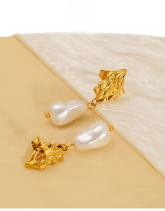 Detailed shot of titanium steel earrings with baroque pearls and textured gold finish