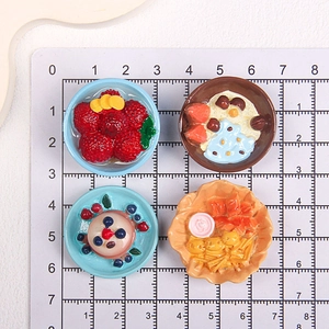 Miniature resin food models on measurement grid featuring cakes and dessert bowls