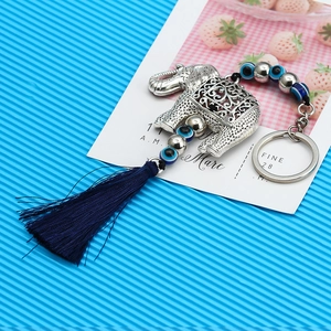 Detail of silver elephant keychain with blue evil eye beads and dark blue tassel accent