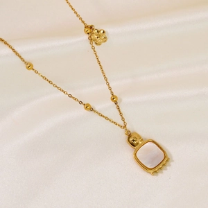 Detail of 14K gold plated flower necklace with white shell pendant on white silk fabric