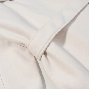Detailed macro view of white wool coat fabric texture and waist belt loop stitching