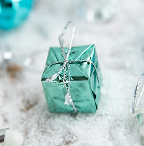 Close-up of cyan blue metallic gift box ornament with silver hanging string decoration