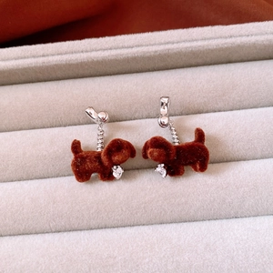 Detailed view of flocked puppy earrings with zircon inlay on a gray velvet jewelry box
