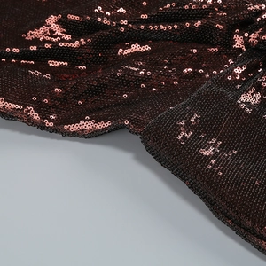 Detailed macro view of deep burgundy sequins on a backless halter jumpsuit fabric