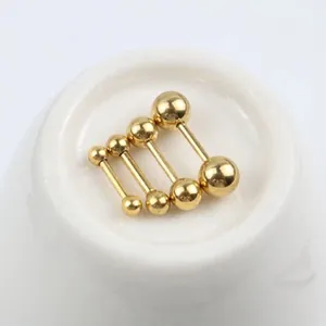Golden stainless steel ball barbell earrings in four different sizes on white ceramic base