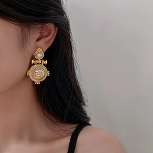Close-up of vintage gold floral earrings with pearls worn by a model for a stylish look