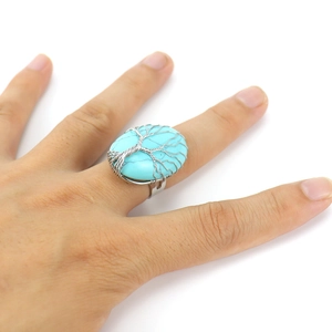 Detailed view of handmade tree of life ring with oval turquoise and silver wire wrap