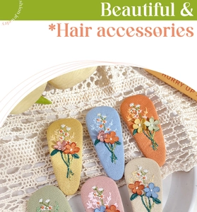 Close-up of floral embroidery detail on fabric-wrapped BB hair clips in various pastel colors