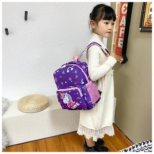 Close-up of a young girl wearing a purple unicorn backpack with rainbow patterns and side mesh pockets