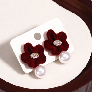 Detail of red velvet flower earrings with crystals and imitation pearls on a stand