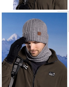 Close-up of grey cable knit hat and neck warmer set against a snowy mountain backdrop