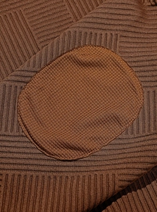 Vista macro del tessuto a maglia marrone con toppa circolare e motivo a coste verticali
