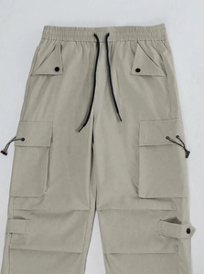 Detail of khaki techwear cargo pants featuring drawstring waist and functional pockets