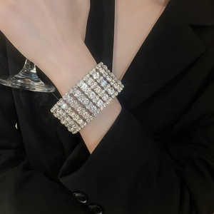 Detail of wide multi-row rhinestone stretch bracelet worn with black suit for luxury style