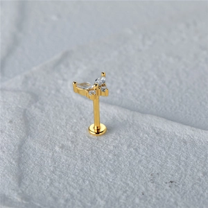 Macro shot of gold butterfly stud with marquise cubic zirconia on a stone surface